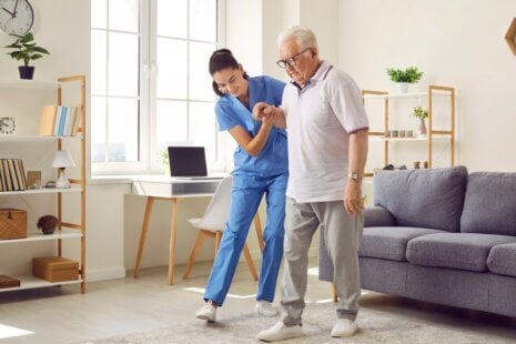 Caregiver providing compassionate in-home senior care to an elderly man in his living room