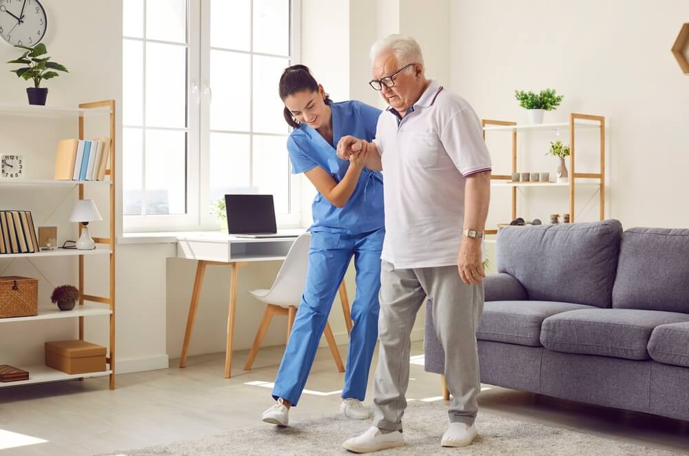 Caregiver providing compassionate in-home senior care to an elderly man in his living room
